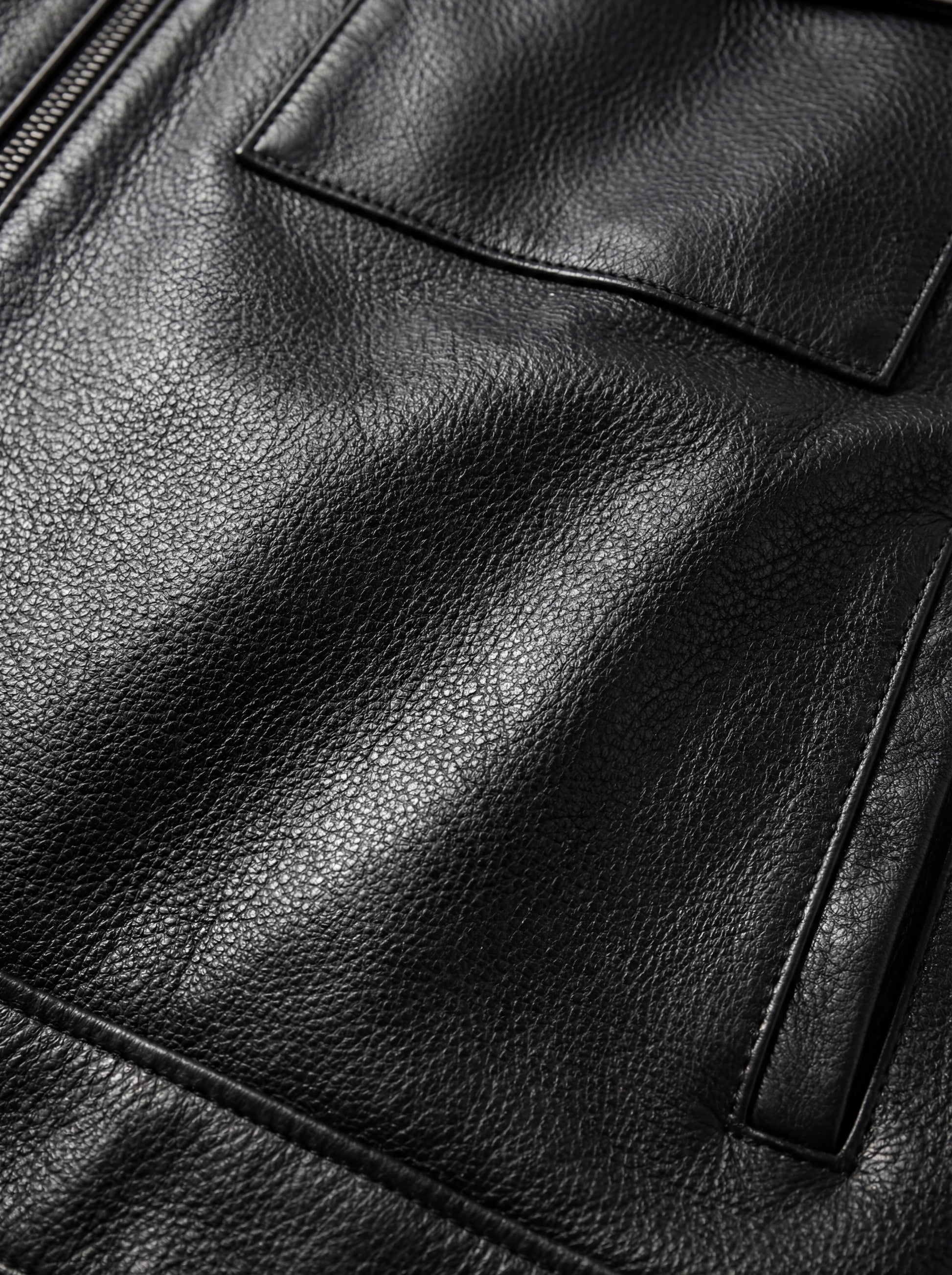 Macro shot of grained black leather texture and chest flap pocket stitching on zip-front shirt. The Spencer by Maverick Jacket.
