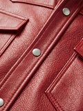 Macro shot of grained red leather texture and silver snap button detail on western shirt. The Griffin by Maverick Jacket.