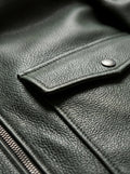 Macro shot of heavy pebbled green leather texture and metal snap button on pocket flap on bomber jacket. The Verdant by Maverick Jacket.