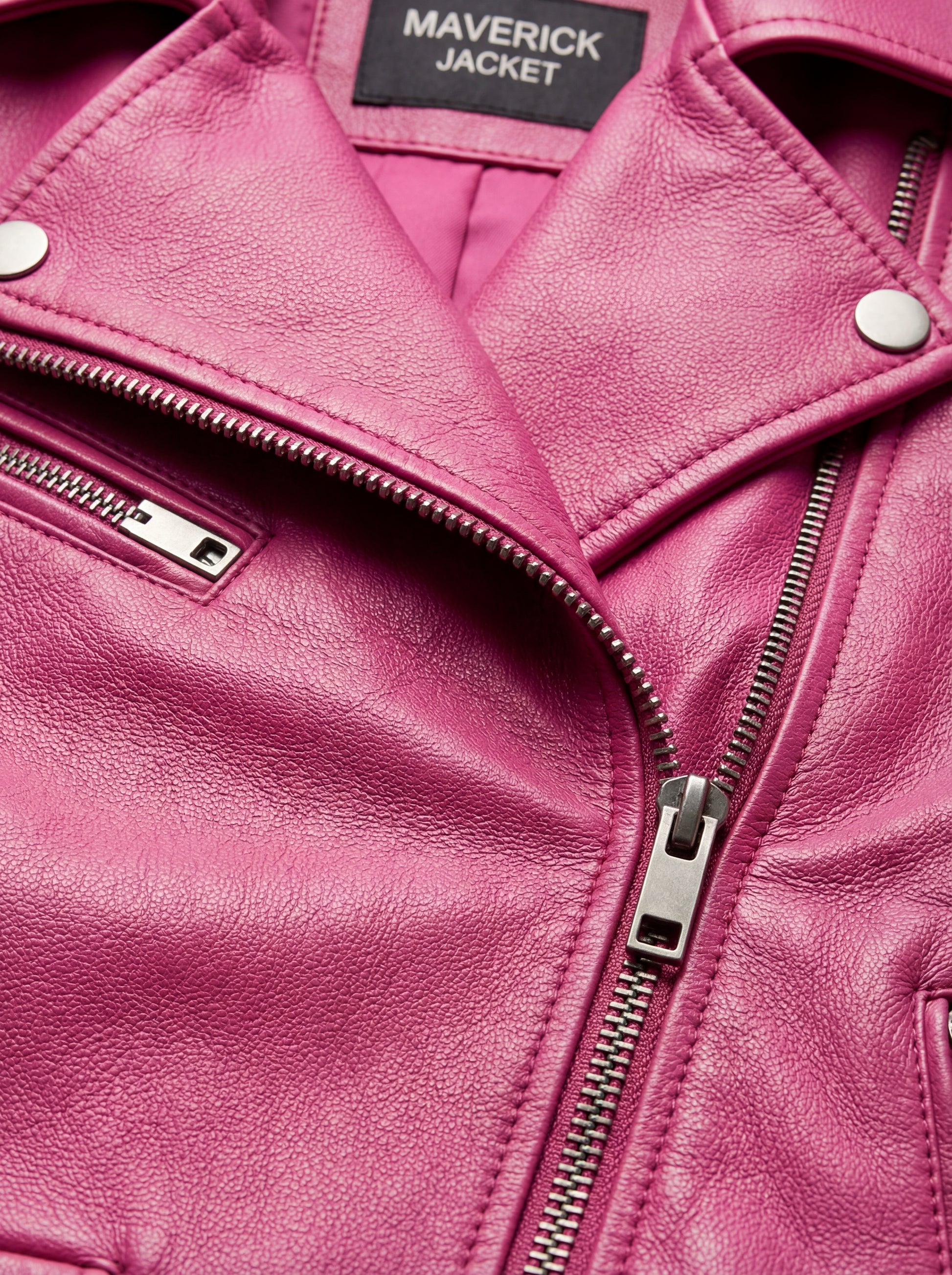 Macro shot of grained fuchsia leather texture and silver zipper lapel detail on biker jacket. The Cleo by Maverick Jacket.