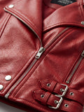 Macro shot of pebbled red leather texture and silver zipper hardware with adjustable buckles on biker jacket. The Vixen by Maverick Jacket.