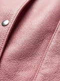 Macro shot of pebbled pink leather texture and silver snap button detail on vest. The Belle by Maverick Jacket.