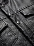 Macro shot of pebbled black leather texture and silver snap button hardware on biker vest. The Oakley by Maverick Jacket.