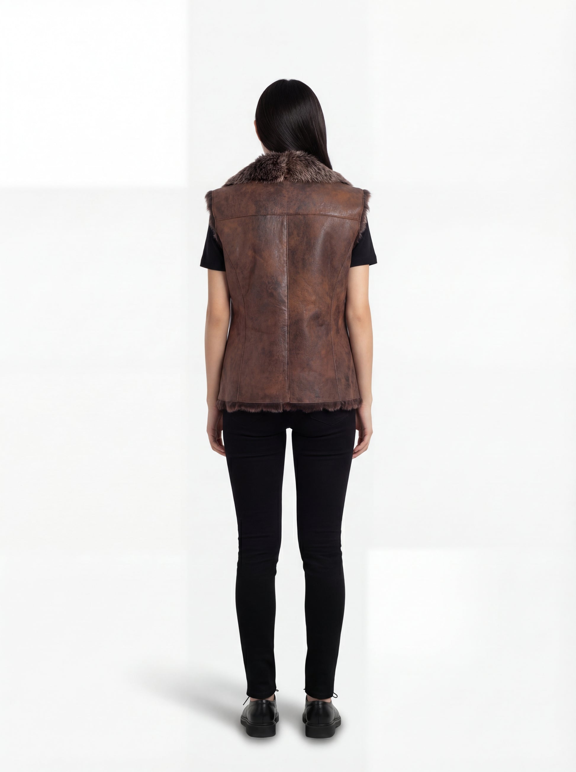 Rear view of female model wearing Maverick Freya leather vest showing fur collar drape and straight back styling. Maverick Jacket.