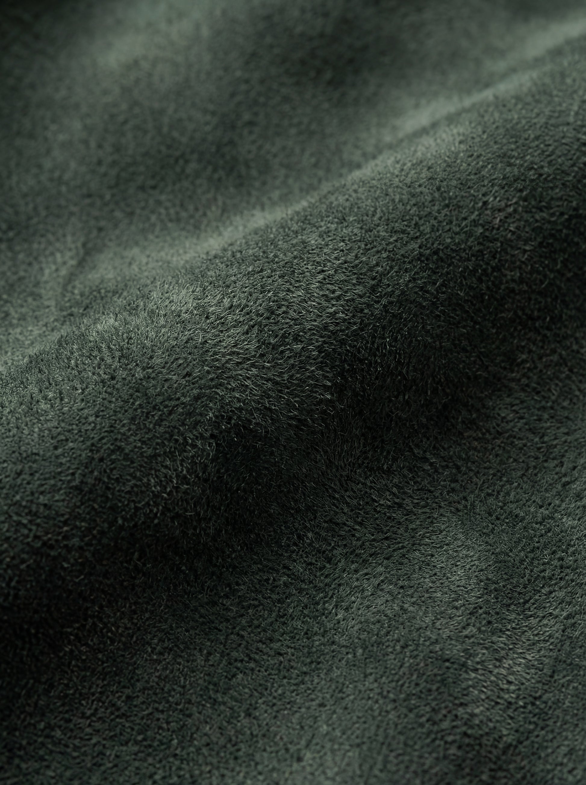 Macro shot of soft green suede texture and silver zipper hardware on bomber jacket. The Willow by Maverick Jacket.