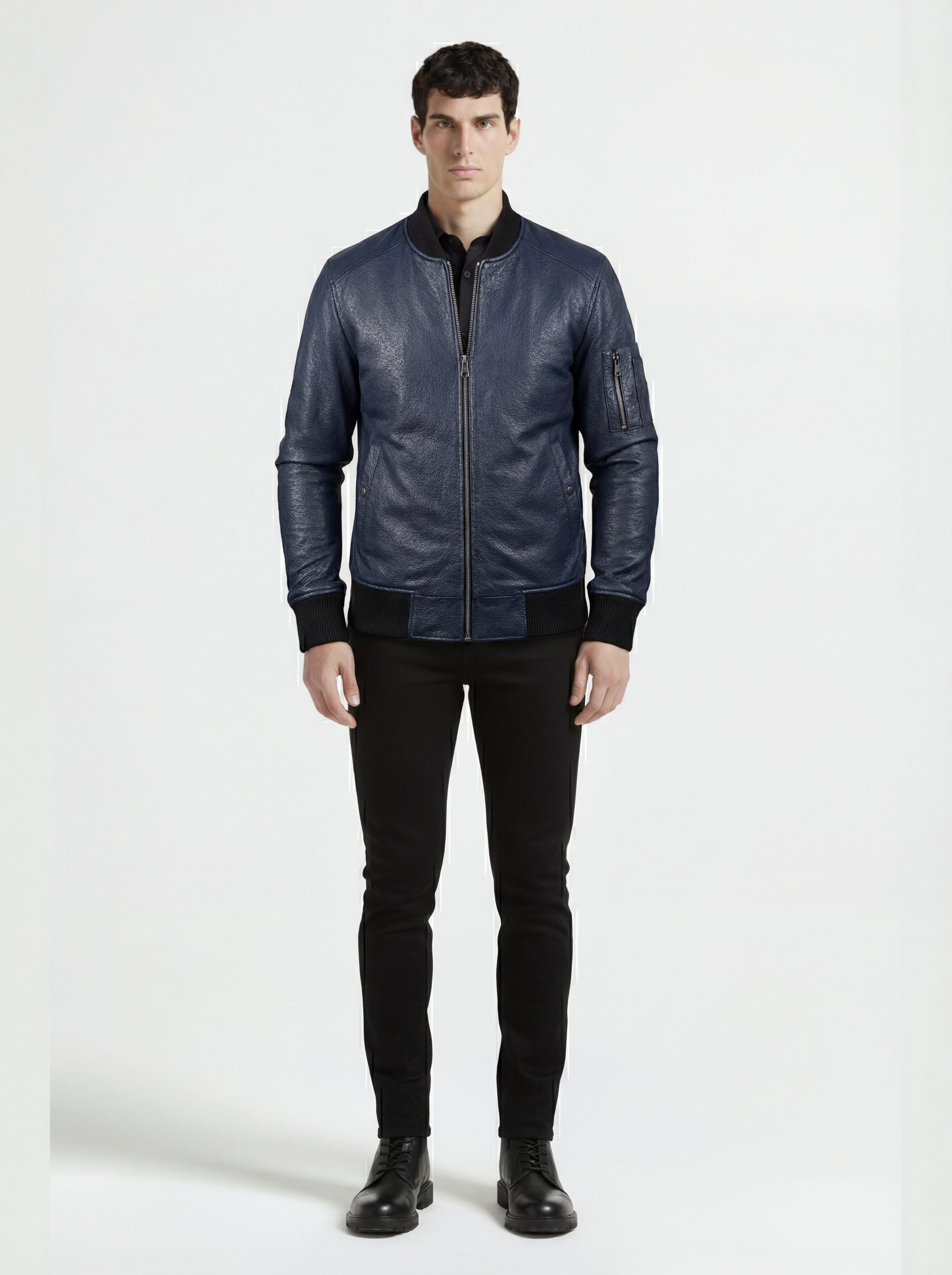 Male model wearing Maverick Stratus navy blue leather bomber, slim fit, styled with black button-down shirt and black skinny jeans. Maverick Jacket.