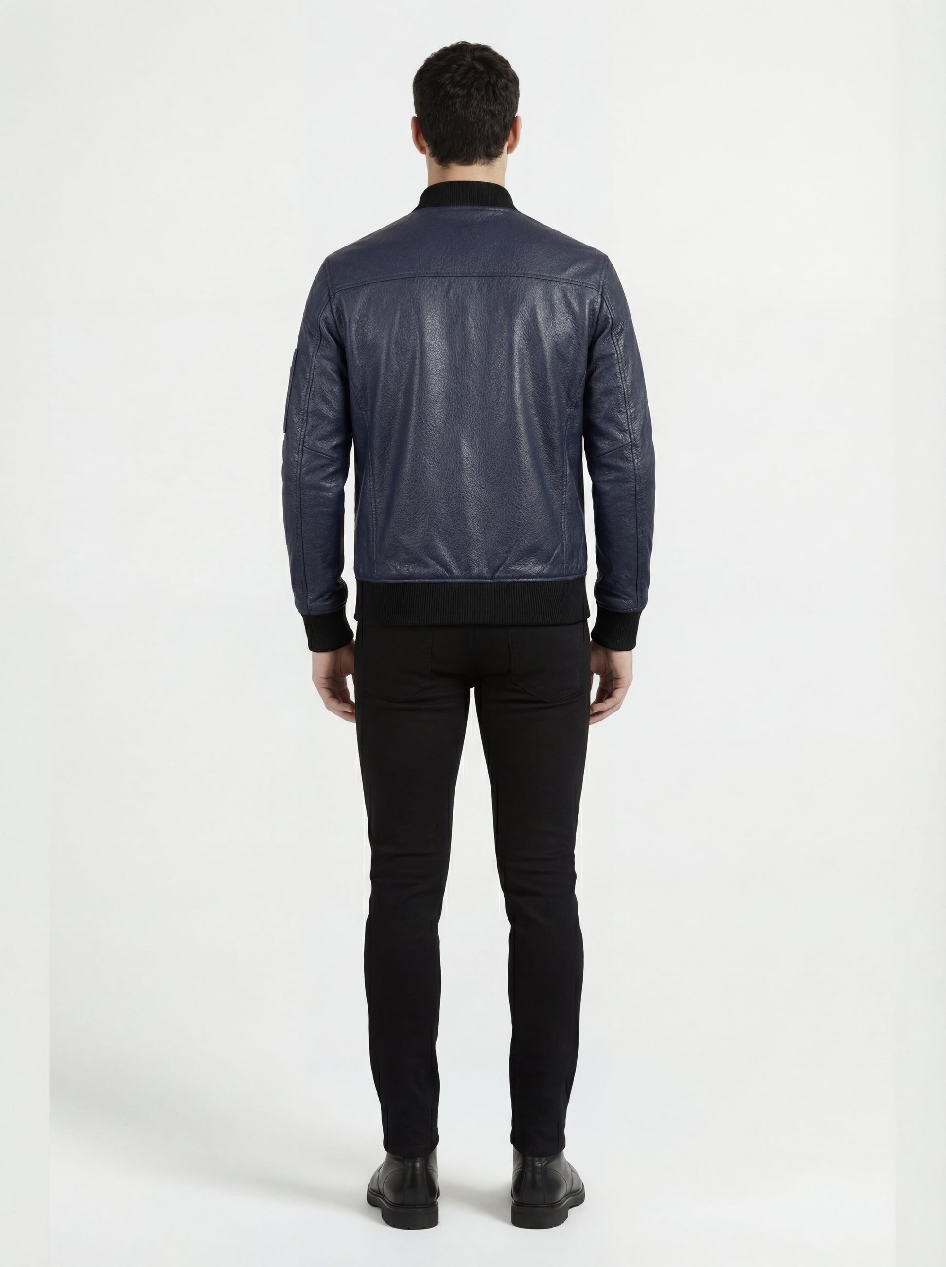 Rear view of male model wearing Maverick Stratus navy blue leather bomber showing fitted shoulder silhouette and ribbed waistband styling. Maverick Jacket.