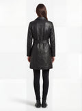 Rear view of female model wearing Maverick Kensington leather trench coat showing structured shoulders and belted waist styling. Maverick Kensington.