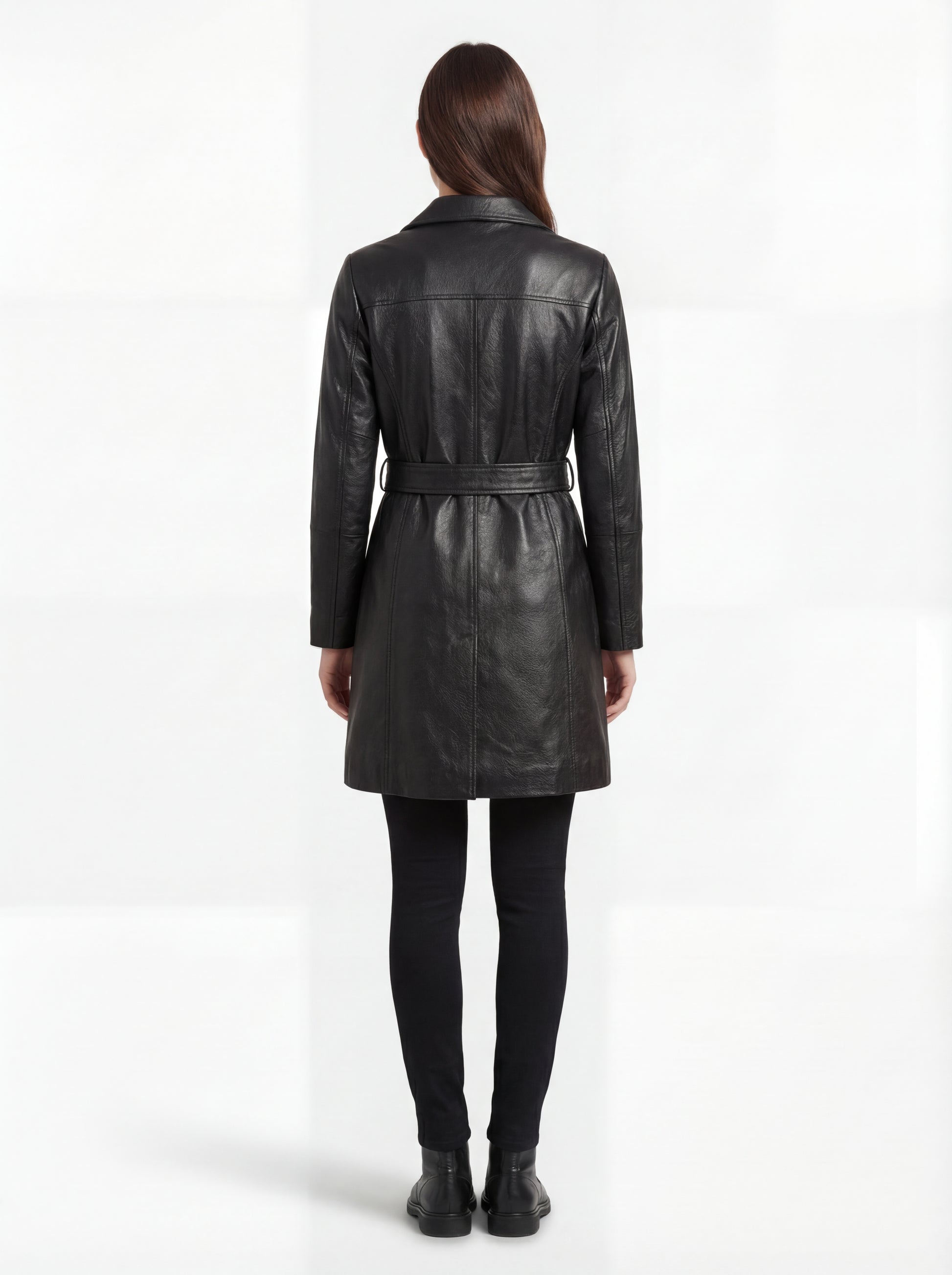 Rear view of female model wearing Maverick Kensington leather trench coat showing structured shoulders and belted waist styling. Maverick Kensington.