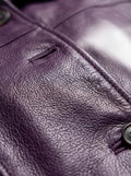 Macro shot of pebbled purple leather texture and buttonhole detail on walker coat. Maverick Helena.