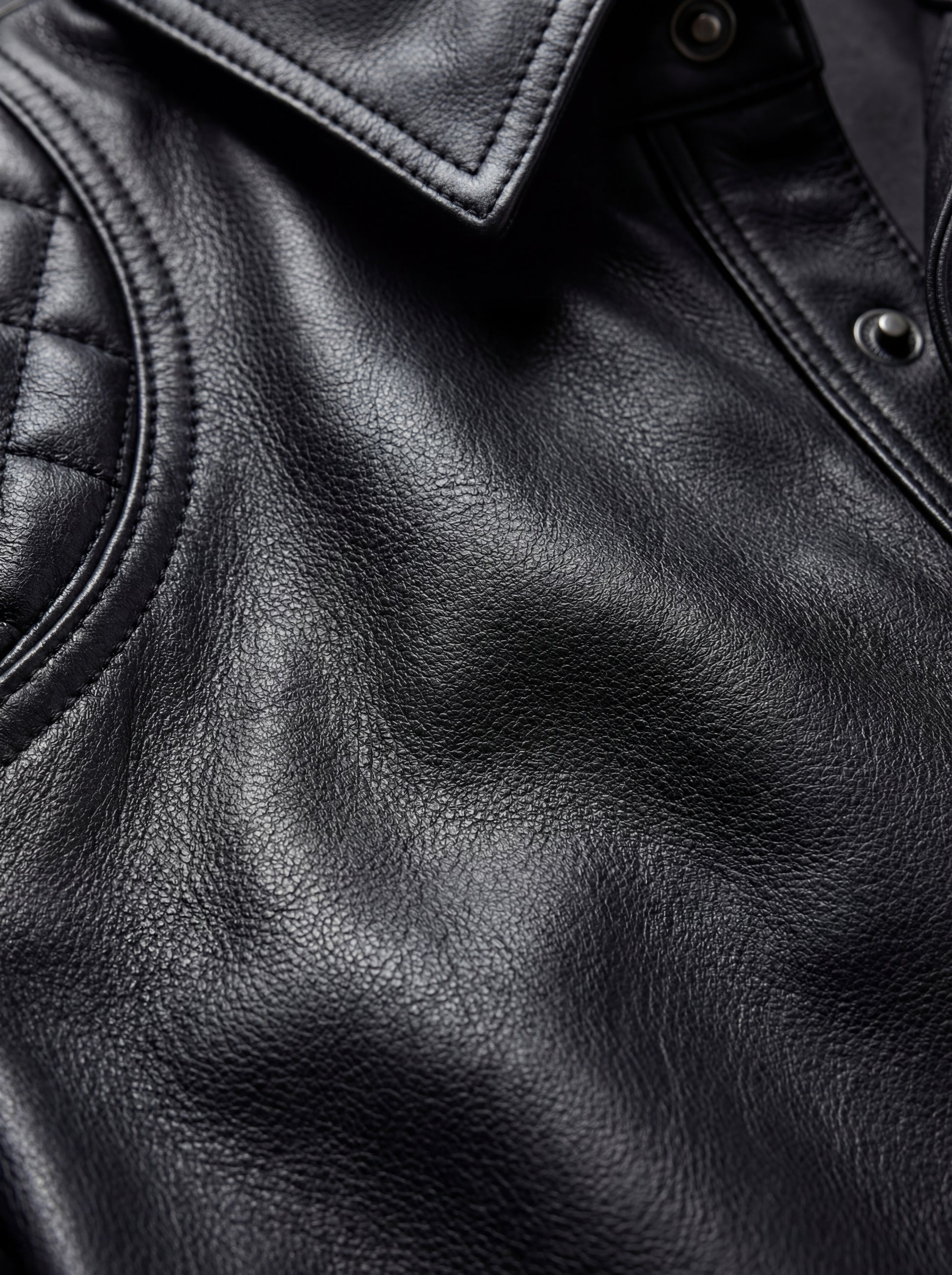 Macro shot of grained black leather texture and diamond quilted stitching on shirt shoulder. The Mason by Maverick Jacket.