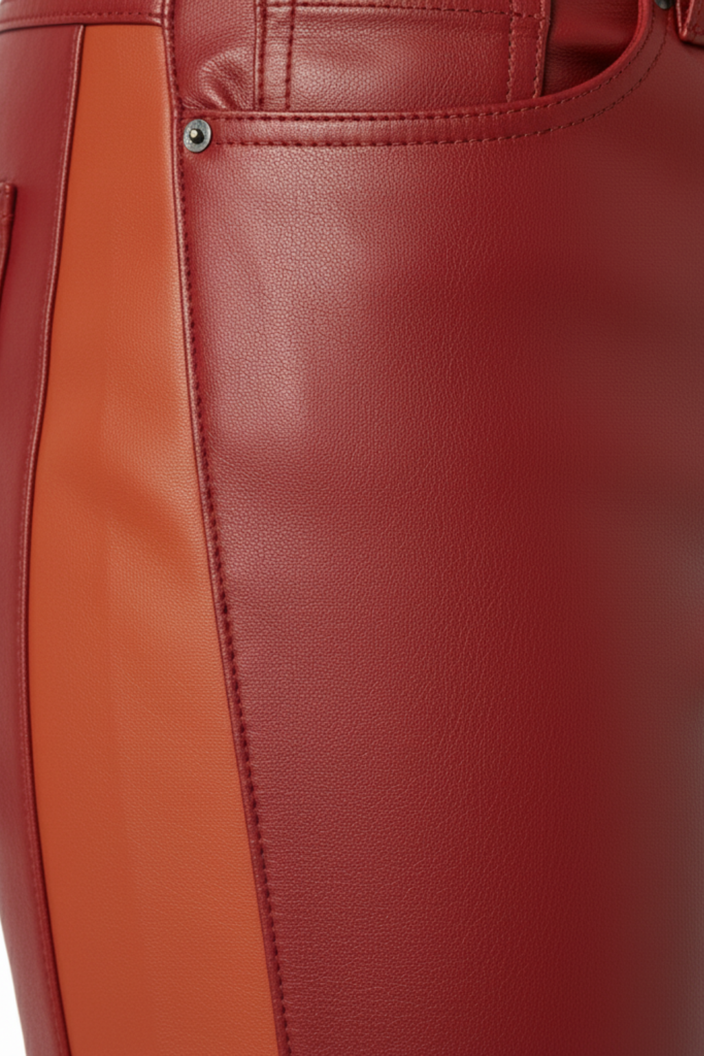 Macro shot of grained red leather texture and silver coin pocket rivet on racing pants. The Jagger by Maverick Jacket.