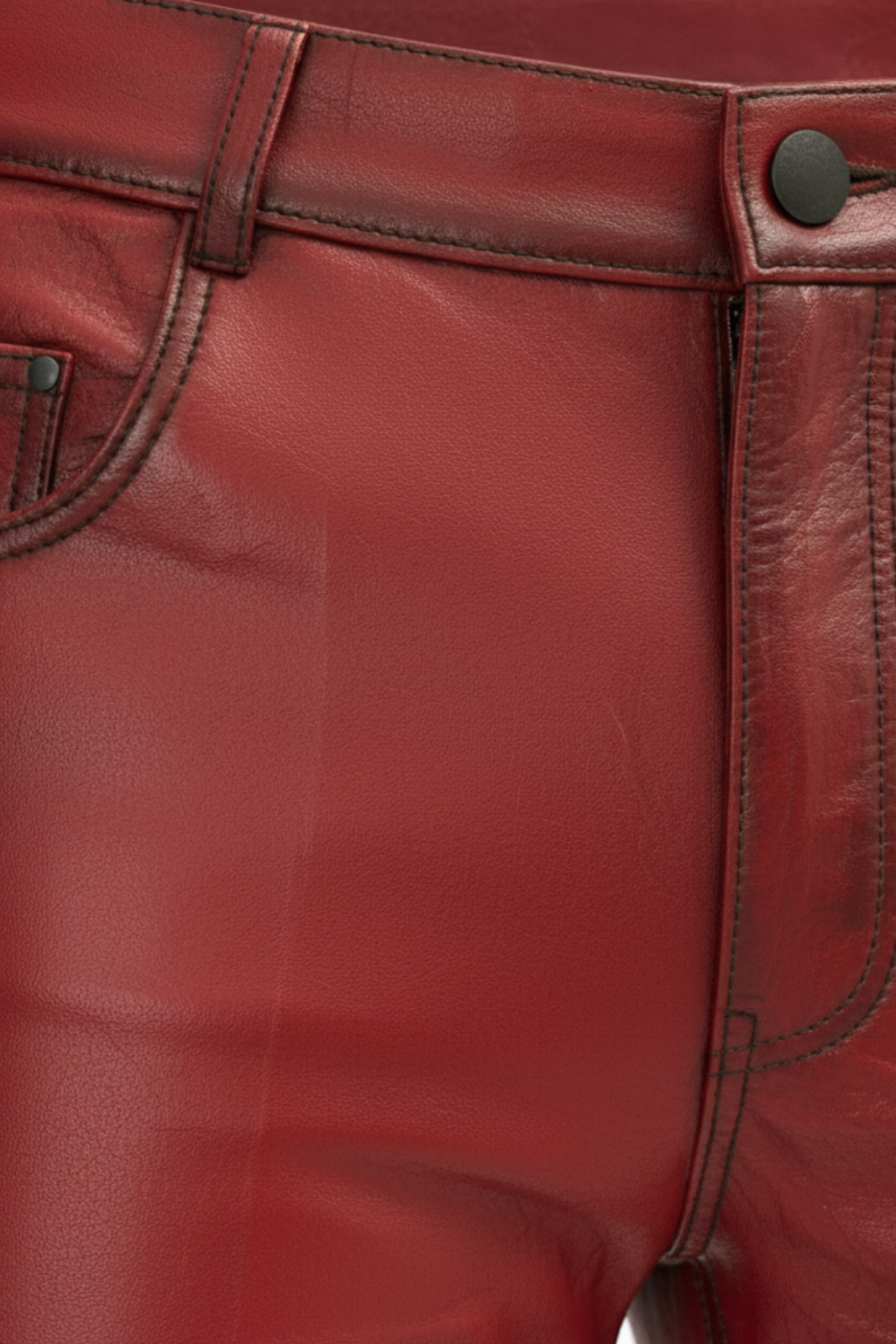 Macro shot of distressed red leather grain and dark button fly hardware on pants. The Knox by Maverick Jacket.