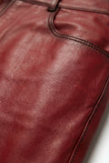 Macro shot of smooth red leather texture and coin pocket stitching on pants. Maverick Knox.