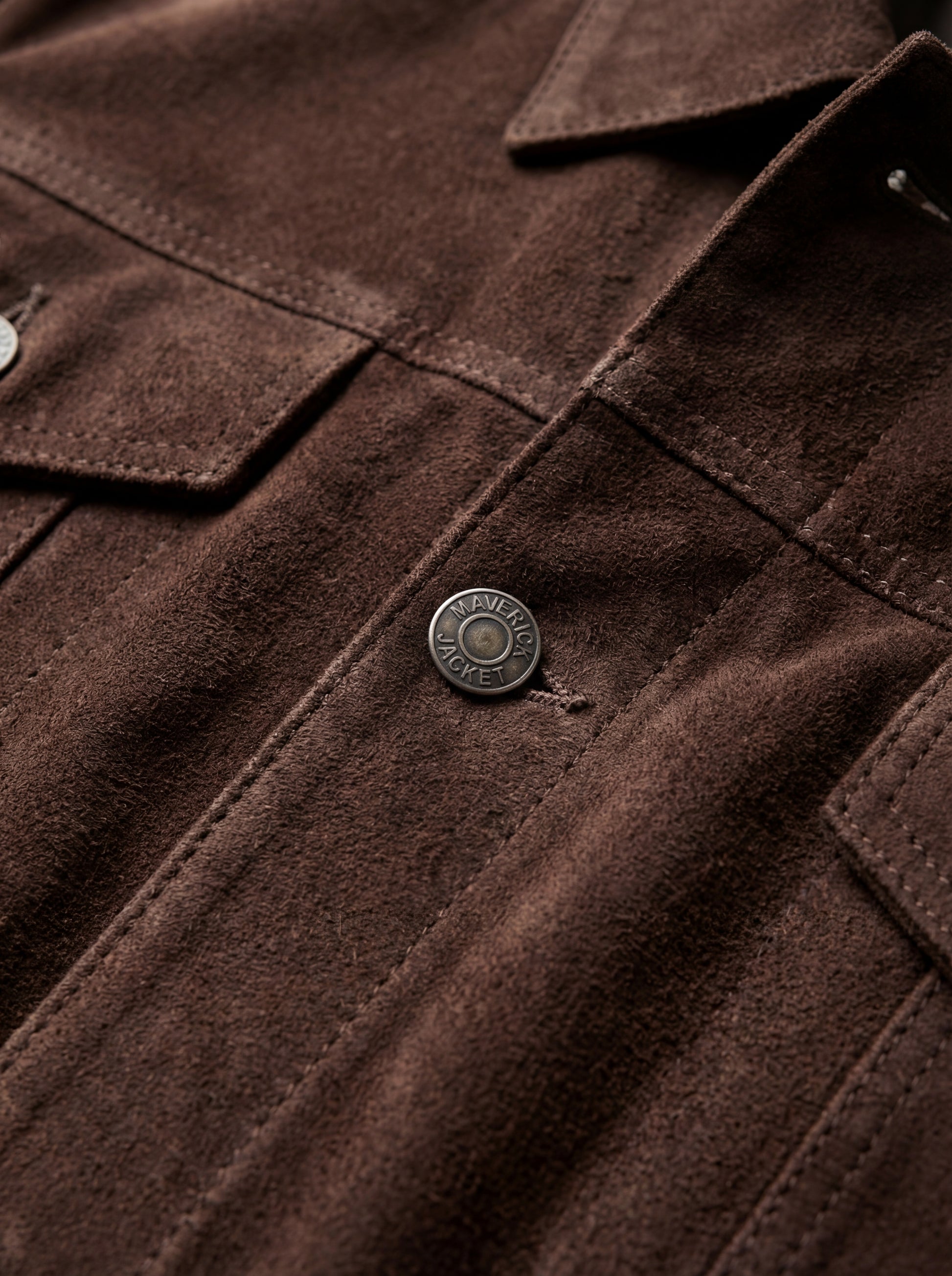 Macro shot of soft brown suede texture and silver hardware detail on trucker jacket. The Callum by Maverick Jacket.