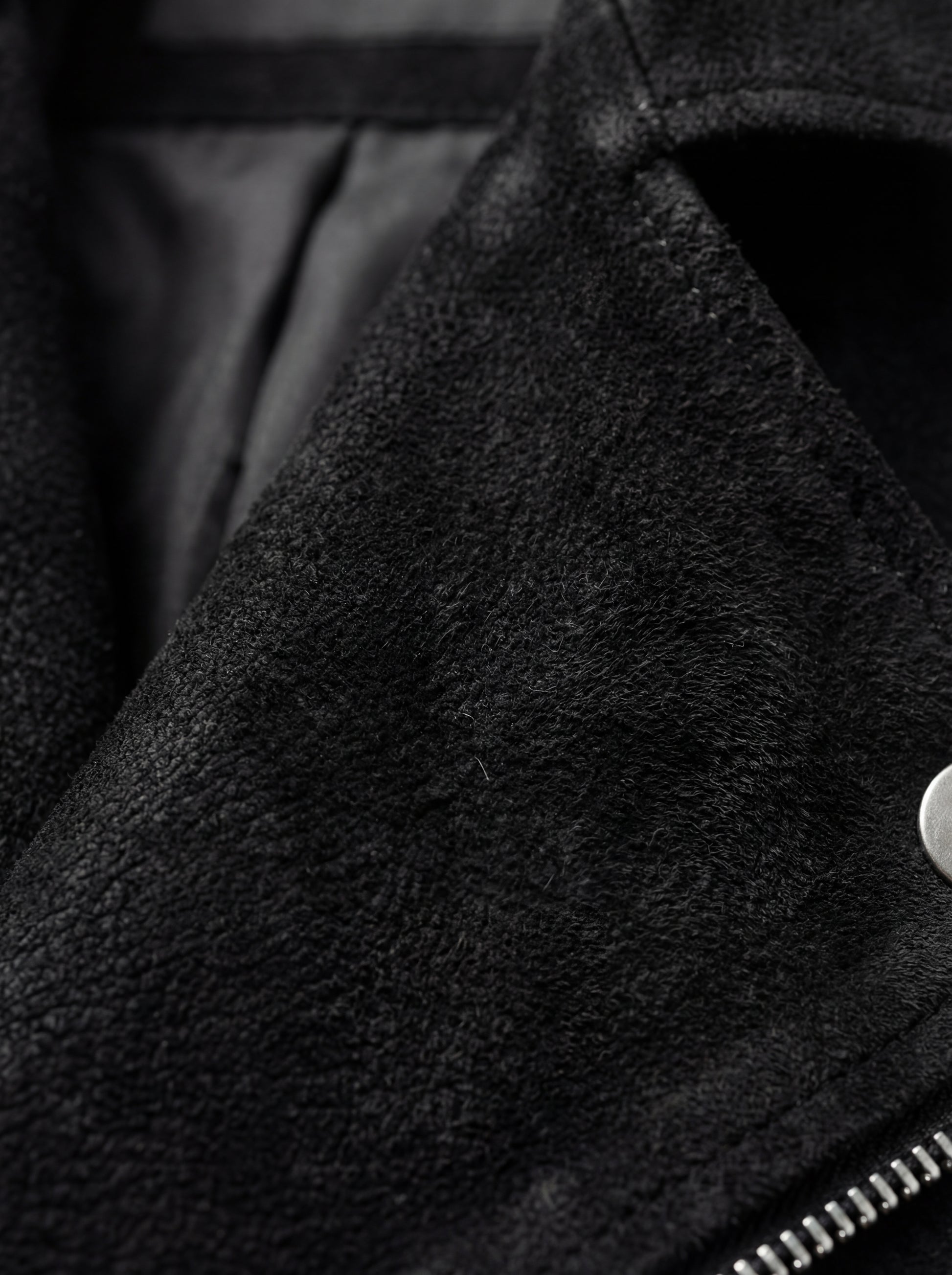 Macro shot of soft black suede texture and silver zipper hardware on biker jacket. The Silas by Maverick Jacket.