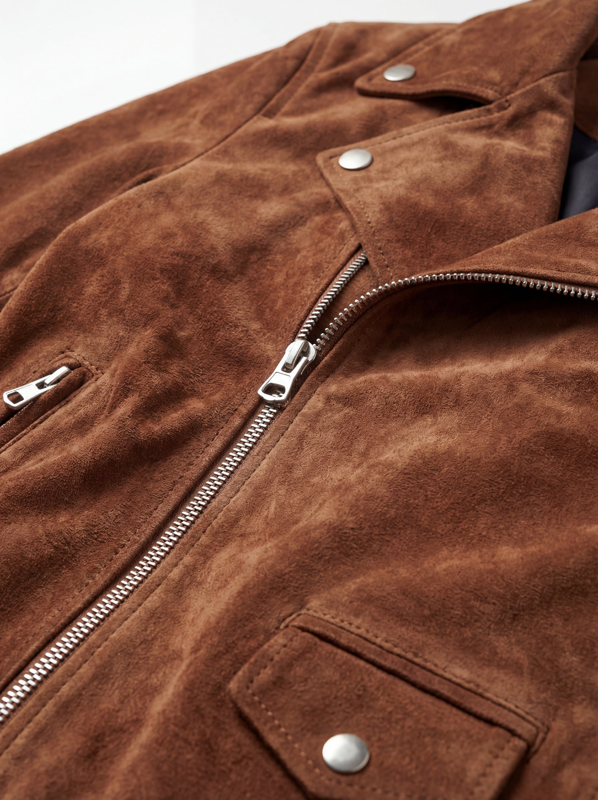 Macro shot of soft brown suede texture and silver zipper hardware on biker jacket. The Canyon by Maverick Jacket.