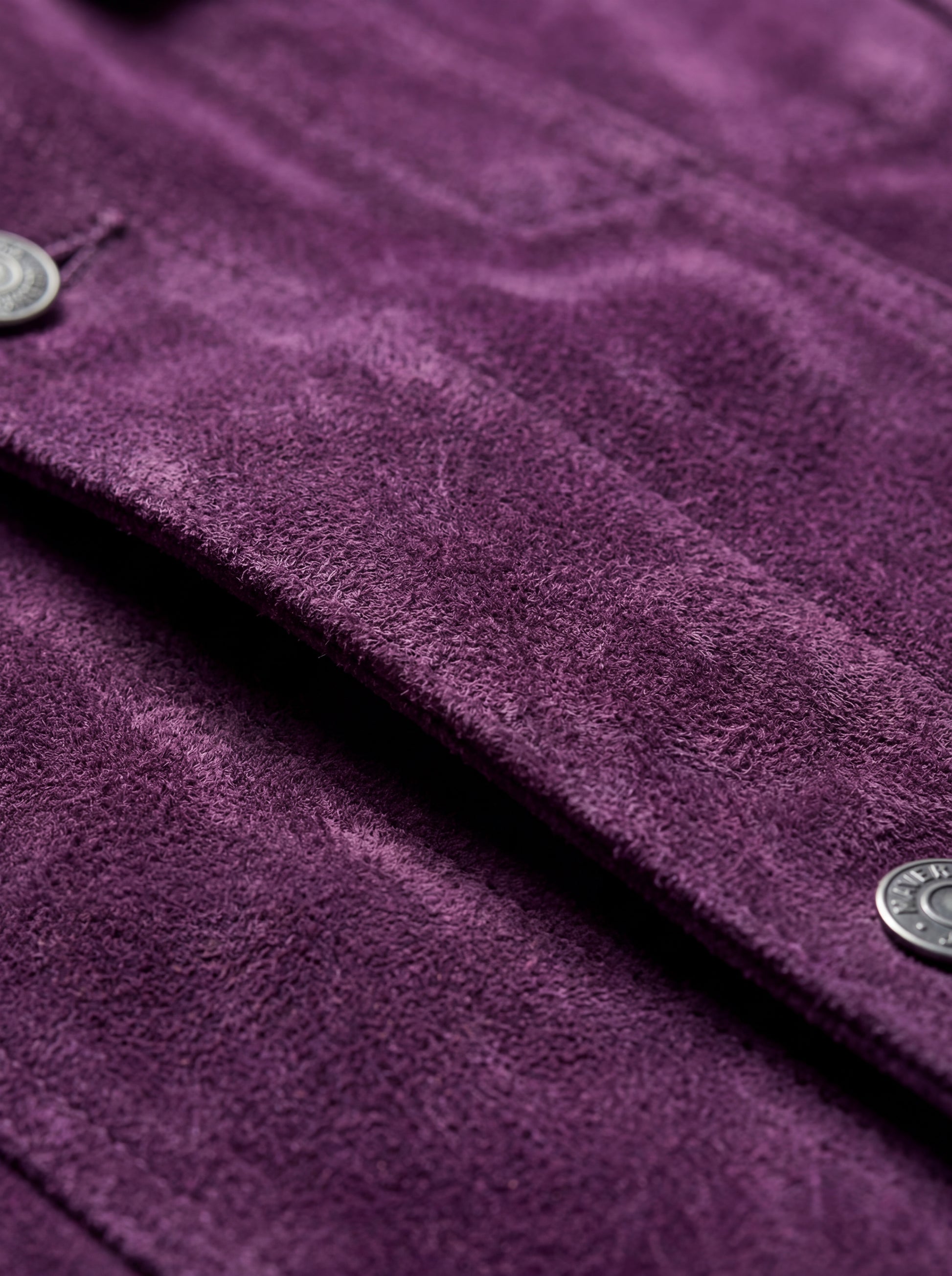 Macro shot of soft purple suede texture and silver hardware detail on trucker jacket. The Prism by Maverick Jacket.