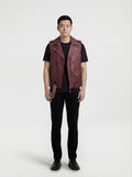Male model wearing Maverick Valor burgundy leather biker vest, slim fit, styled over a black hoodie with ripped charcoal denim jeans. Maverick Jacket.