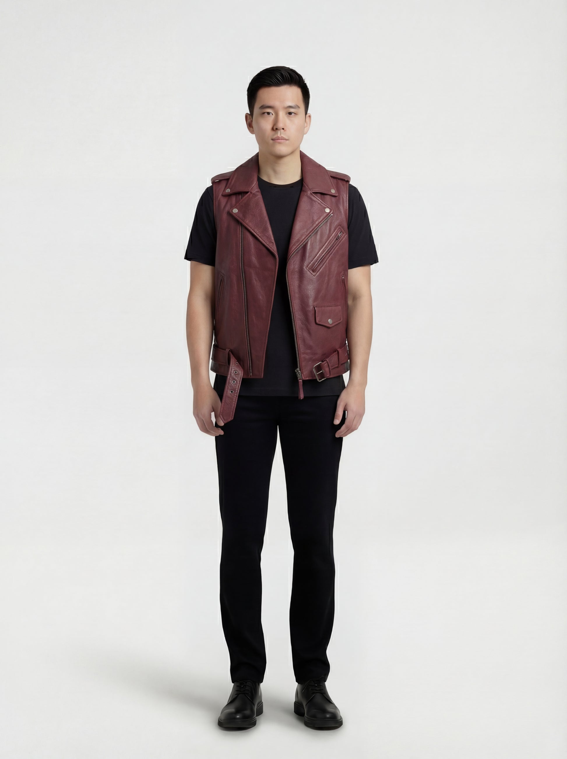 Male model wearing Maverick Valor burgundy leather biker vest, slim fit, styled over a black hoodie with ripped charcoal denim jeans. Maverick Jacket.