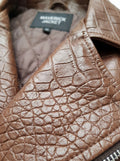 Macro shot of textured croc-embossed leather skin and heavy-duty silver zipper on biker vest. The Drake by Maverick Jacket.