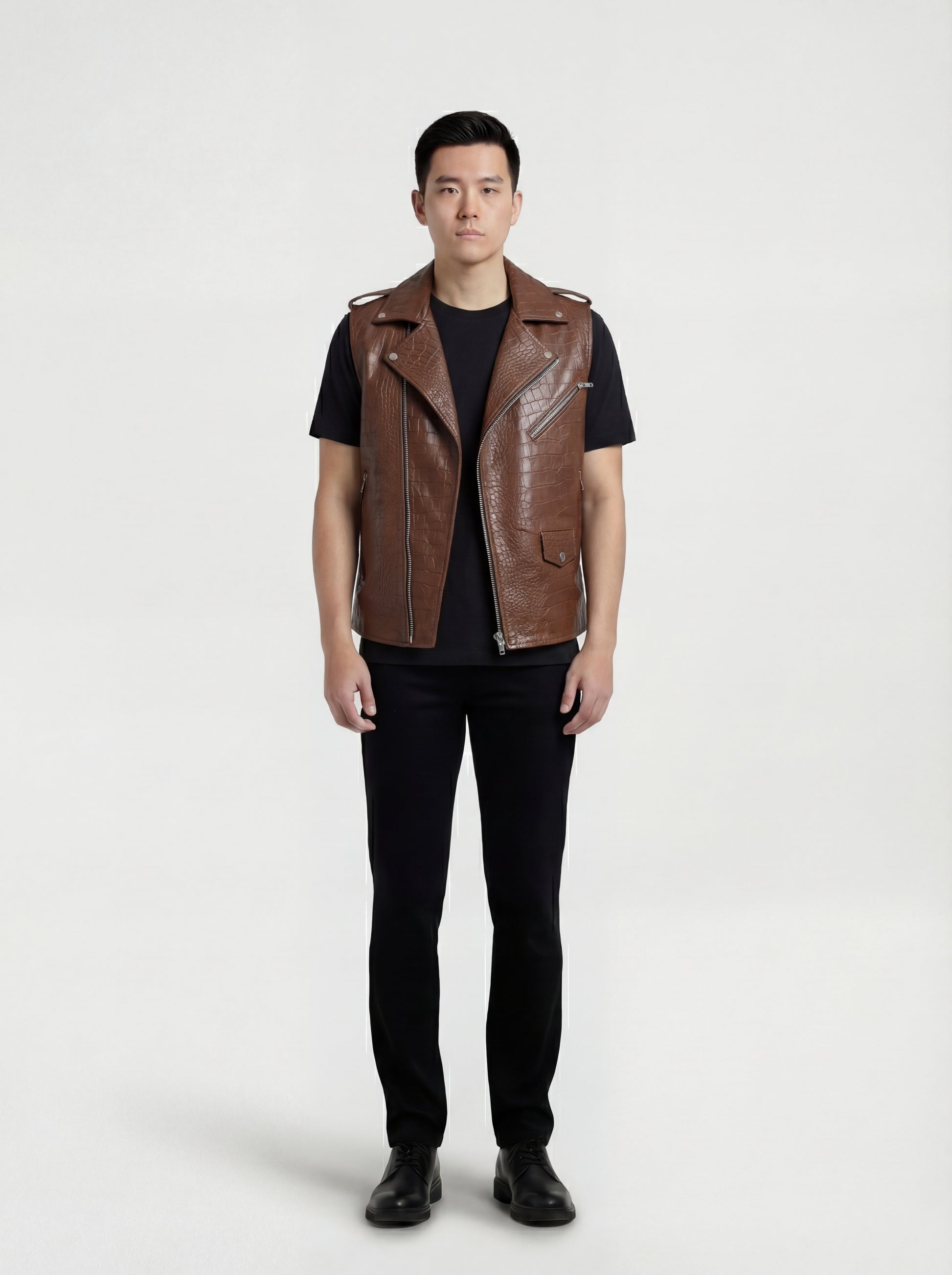 Male model wearing Maverick Drake croc-embossed leather biker vest, slim fit, styled over a black hoodie with ripped charcoal denim jeans. Maverick Jacket.