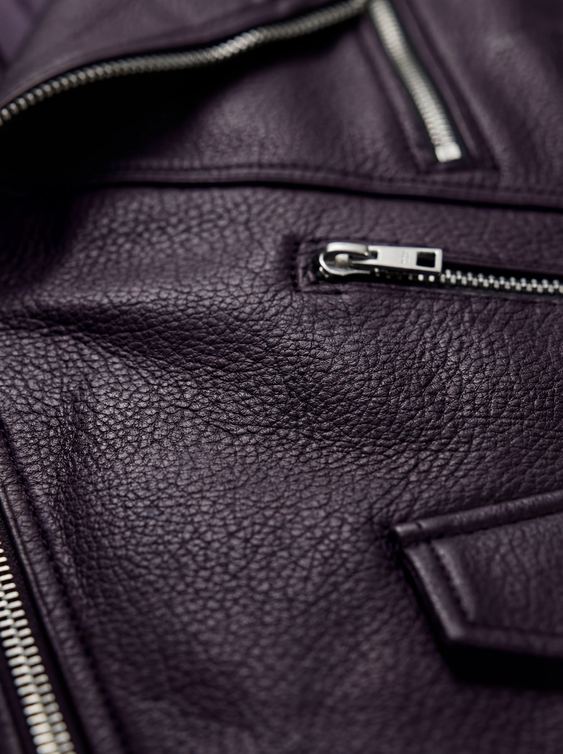 Macro shot of smooth leather texture and heavy-duty metal zipper hardware on biker vest. The Rocco by Maverick Jacket.
