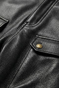 Macro shot of black pebbled leather texture and gold snap button hardware on cargo pants. The Tristan by Maverick Jacket.