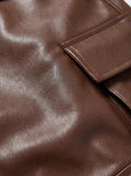 Macro shot of grained saddle brown leather texture and topstitched flap pocket detail on trousers. The Cassian by Maverick Jacket.