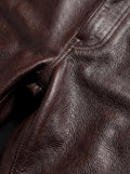 Macro shot of grained leather texture and heavy reinforced stitching on trousers. The Kade by Maverick Jacket.