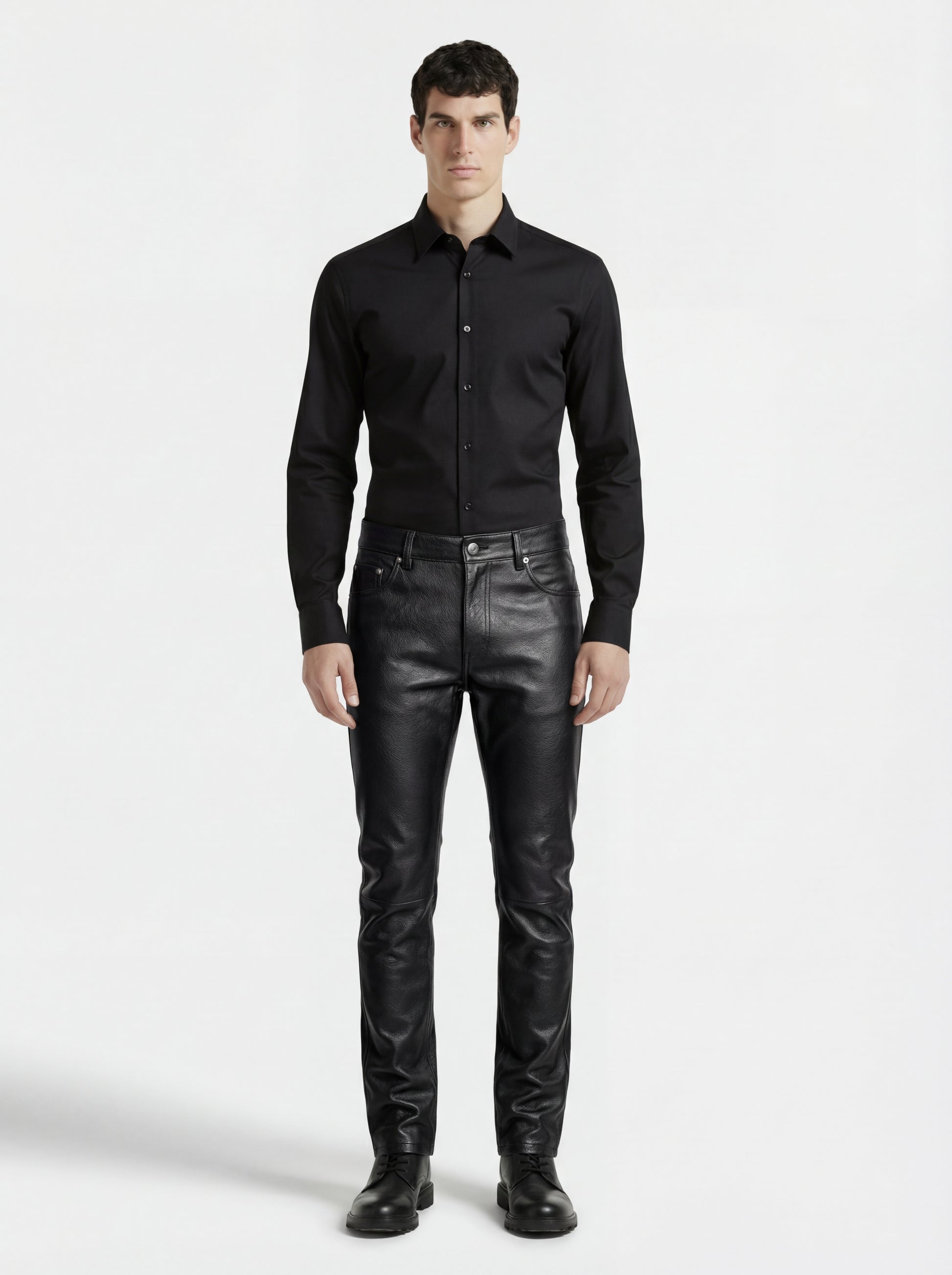 Male model wearing Maverick Caliber black pebbled leather pant, slim fit, styled with black button-up shirt and black leather boots. Maverick Jacket.