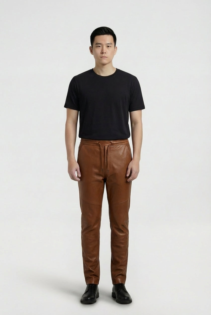Male model wearing Maverick Caelan brown leather jogger pants, tapered fit, styled with black crew neck t-shirt and black leather boots. Maverick Jacket.