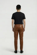 Rear view of male model wearing Maverick Caelan brown leather jogger pants showing relaxed seat fit and rear welt pockets. Maverick Jacket.