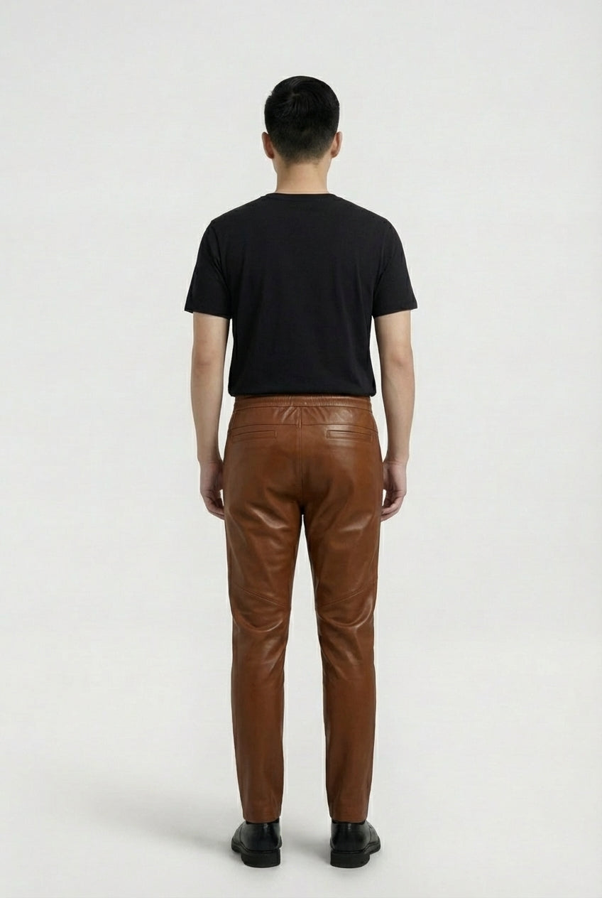 Rear view of male model wearing Maverick Caelan brown leather jogger pants showing relaxed seat fit and rear welt pockets. Maverick Jacket.