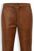 Macro shot of smooth brown leather grain and slanted pocket stitching on jogger pants. The Caelan by Maverick Jacket.