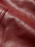 Macro shot of grained red leather texture and reinforced stitching on cargo pocket flap. The Cassian by Maverick Jacket.