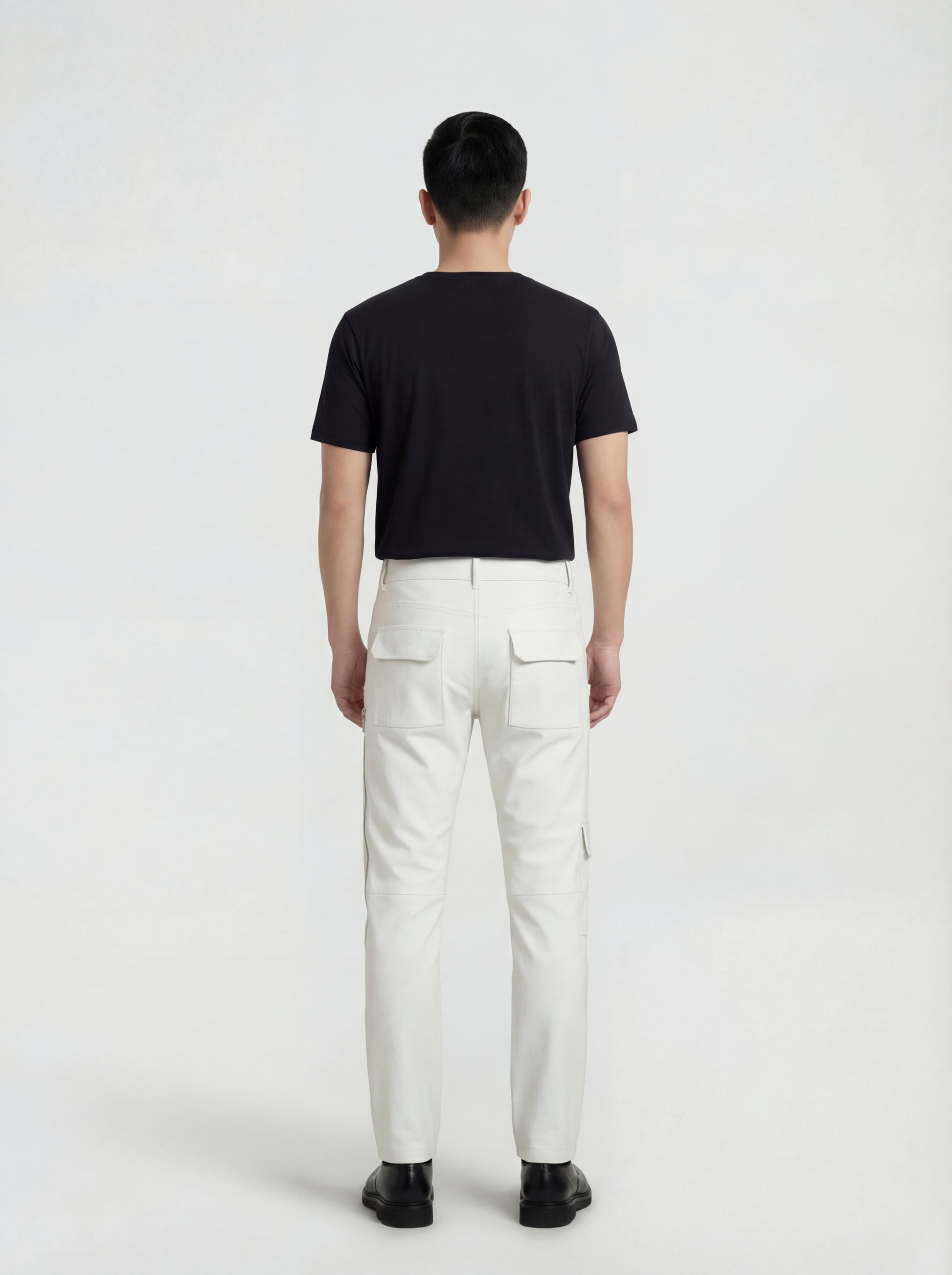 Rear view of male model wearing Maverick Spectre bone white leather cargo trousers showing fitted seat silhouette and straight leg cut. Maverick Jacket.