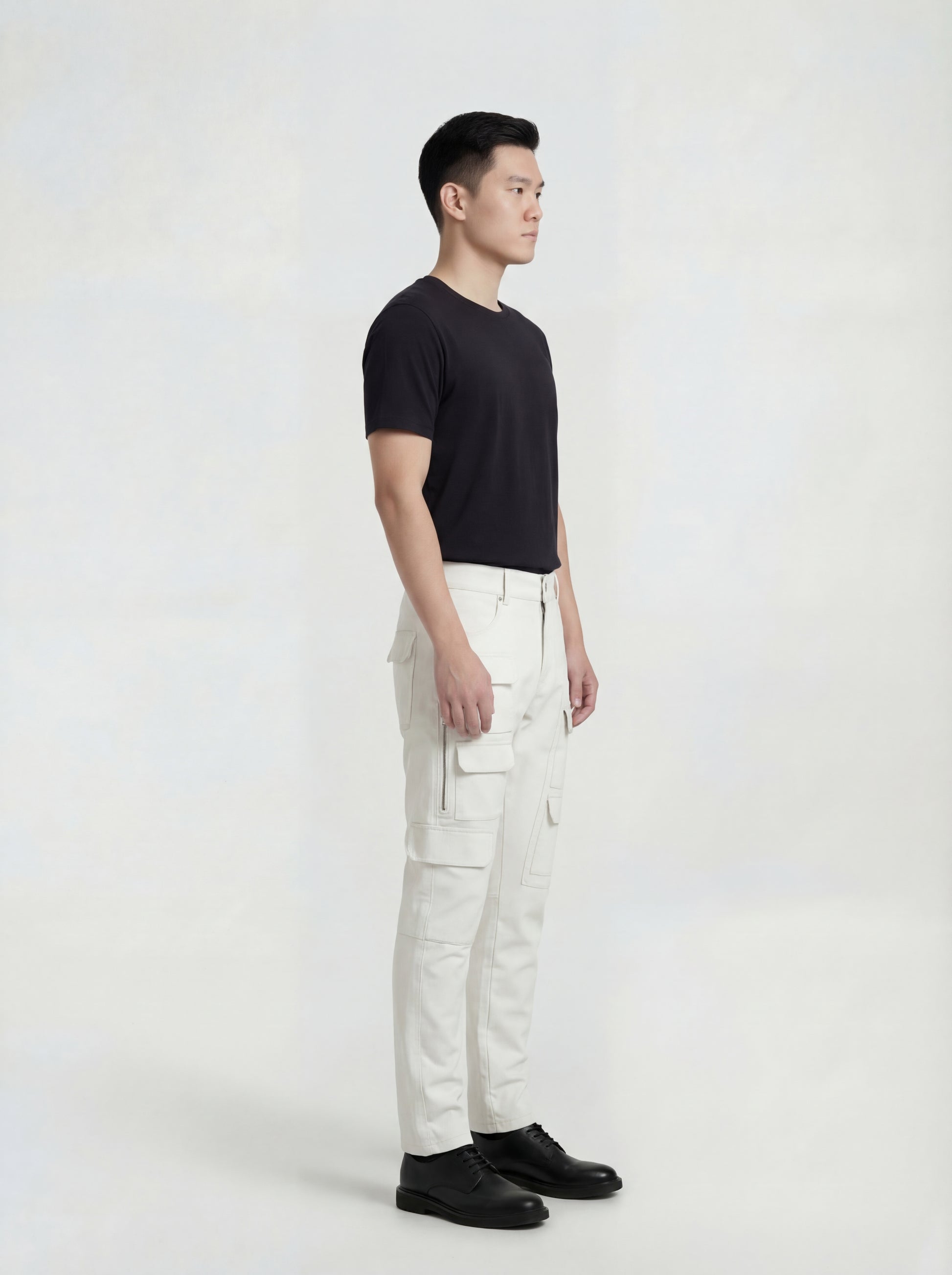 Side profile of Maverick Spectre bone white leather cargo trousers showing zippered cargo pocket detail and straight leg fit. Maverick Jacket.