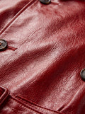 Macro shot of pebbled red leather texture and dark button detailing on trench coat. The Valerian by Maverick Jacket.