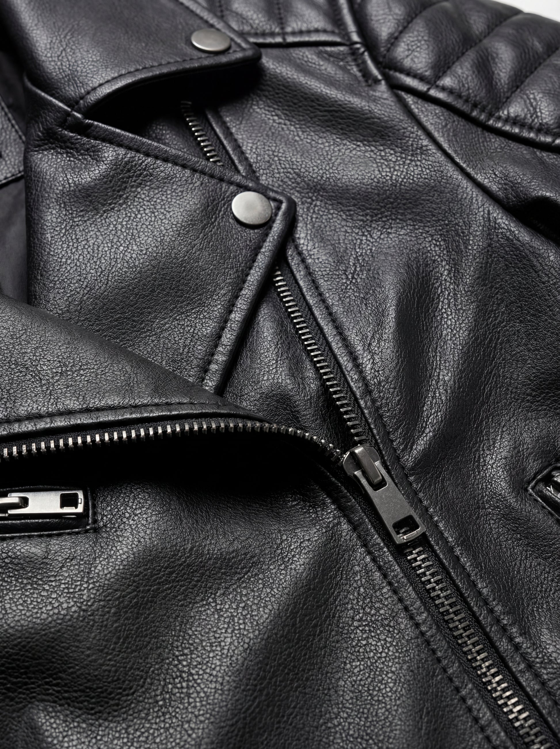 Macro shot of grained black leather texture and silver zipper lapel detail on biker jacket. The Scarlett by Maverick Jacket.