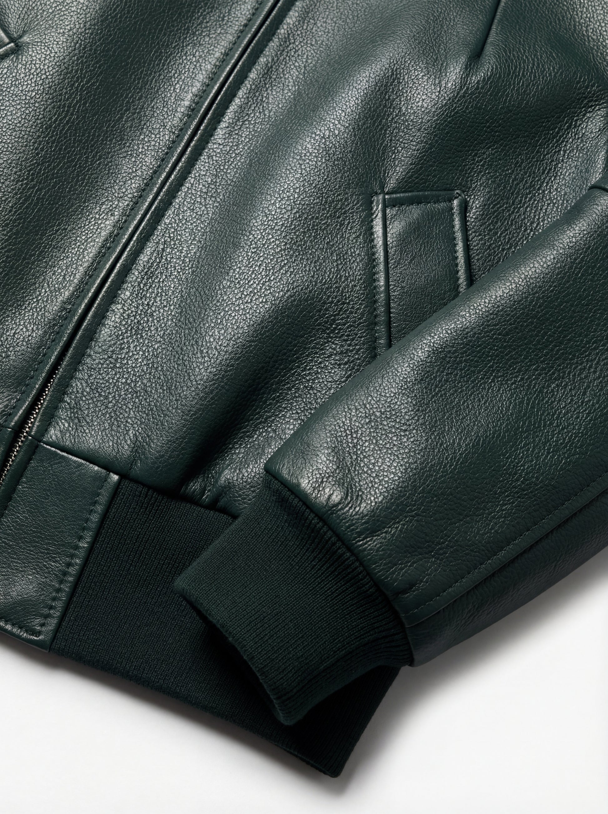 Macro shot of grained green leather texture and ribbed knit cuff detail on bomber jacket. The Isla by Maverick Jacket.