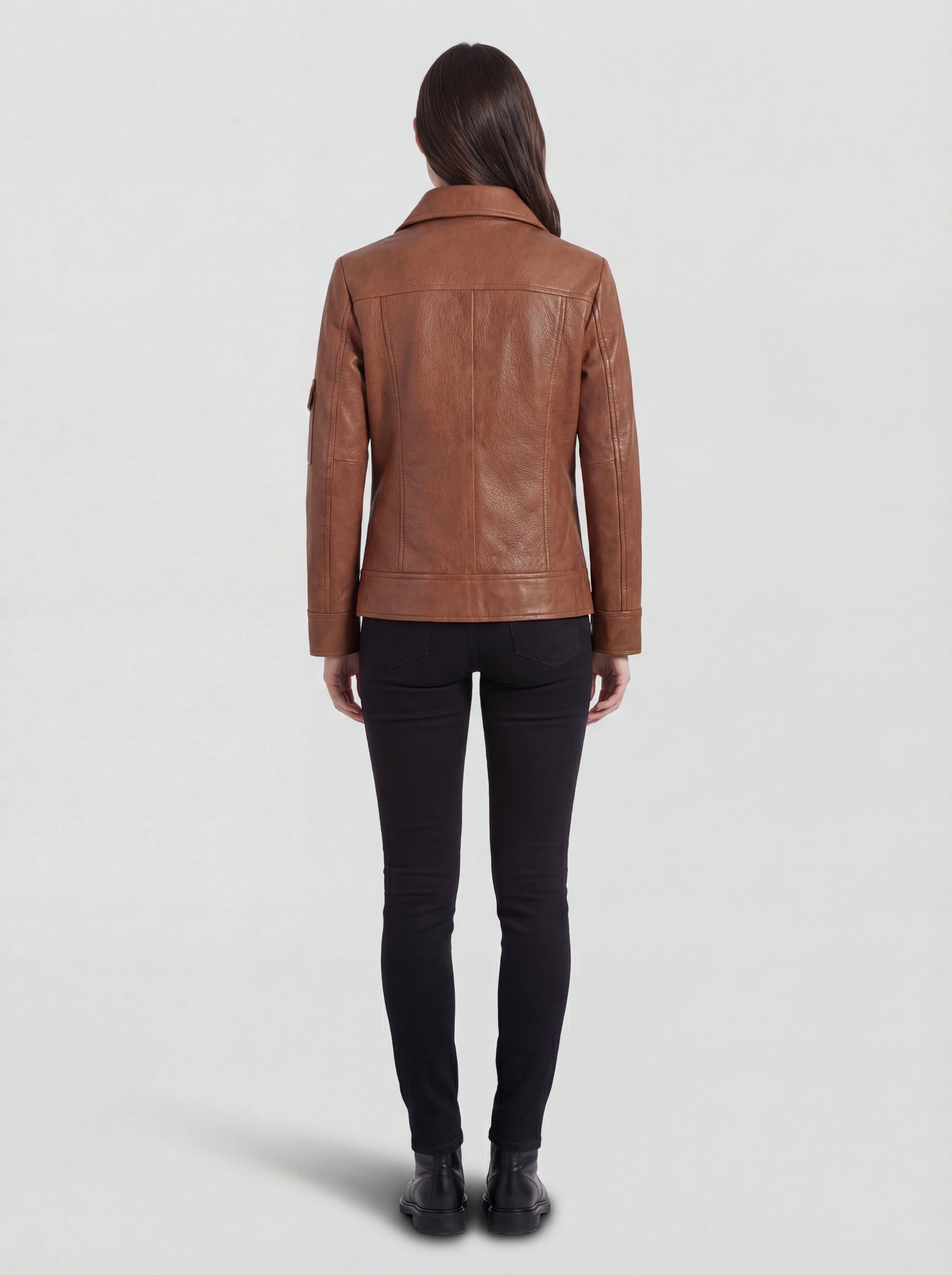 Rear view of female model wearing Maverick Quinn leather utility jacket showing structured shoulder fit and clean back paneling. Maverick Jacket.