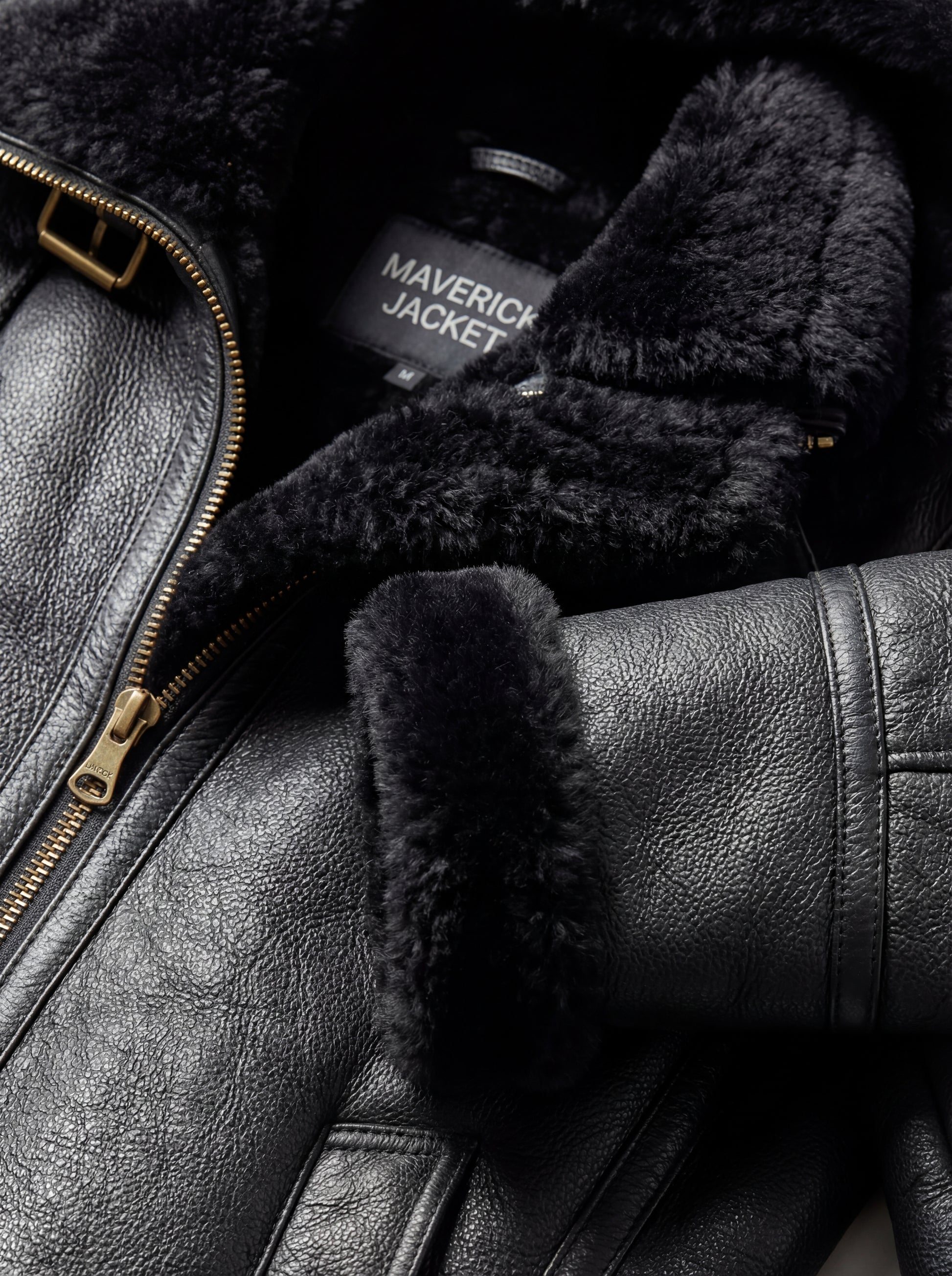Macro shot of pebbled black leather grain and soft black shearling texture on collar. The Kira by Maverick Jacket.