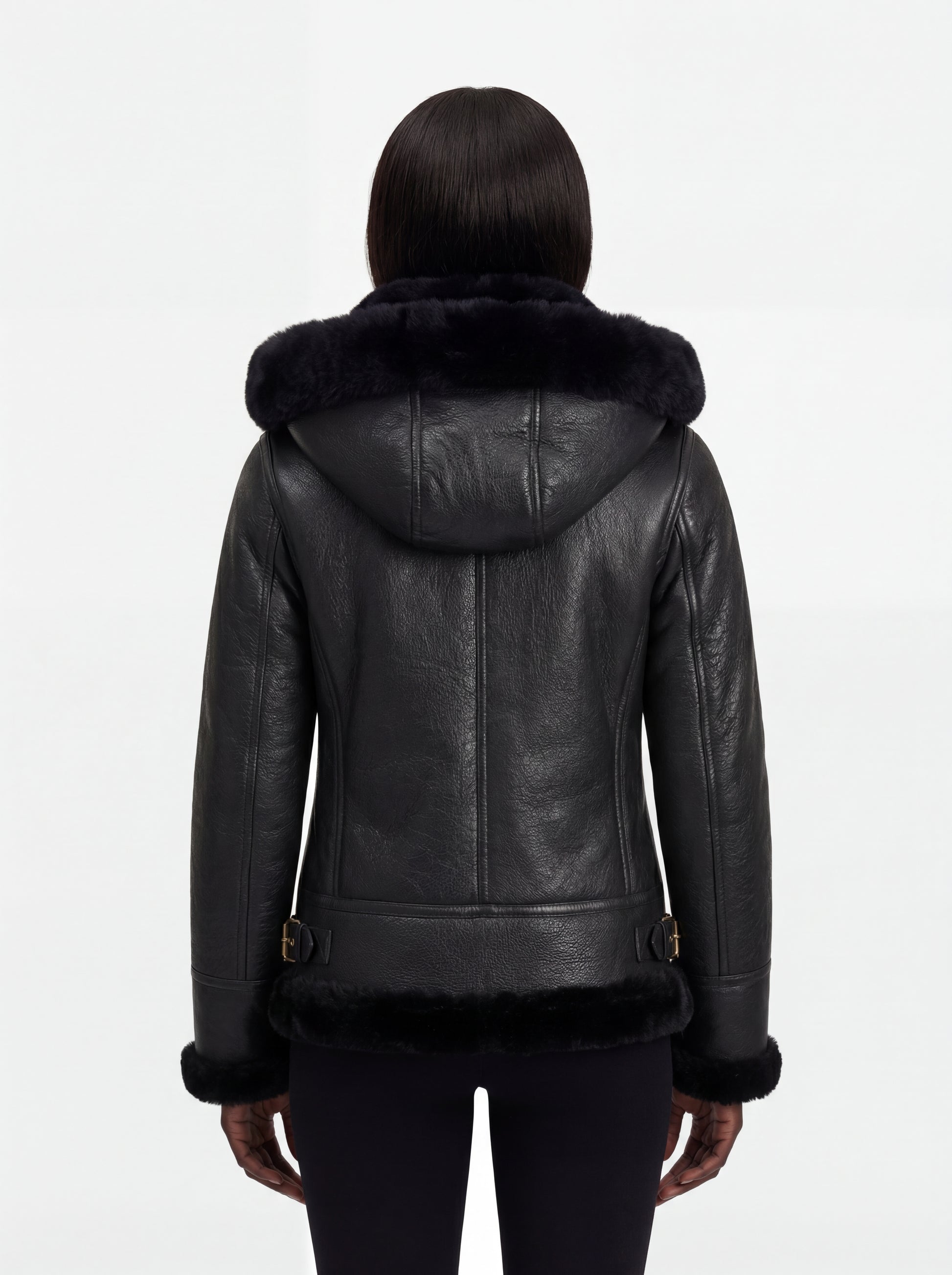 Rear view of female model wearing Maverick Kira hooded shearling jacket showing structured shoulder fit and hood drape. Maverick Jacket.