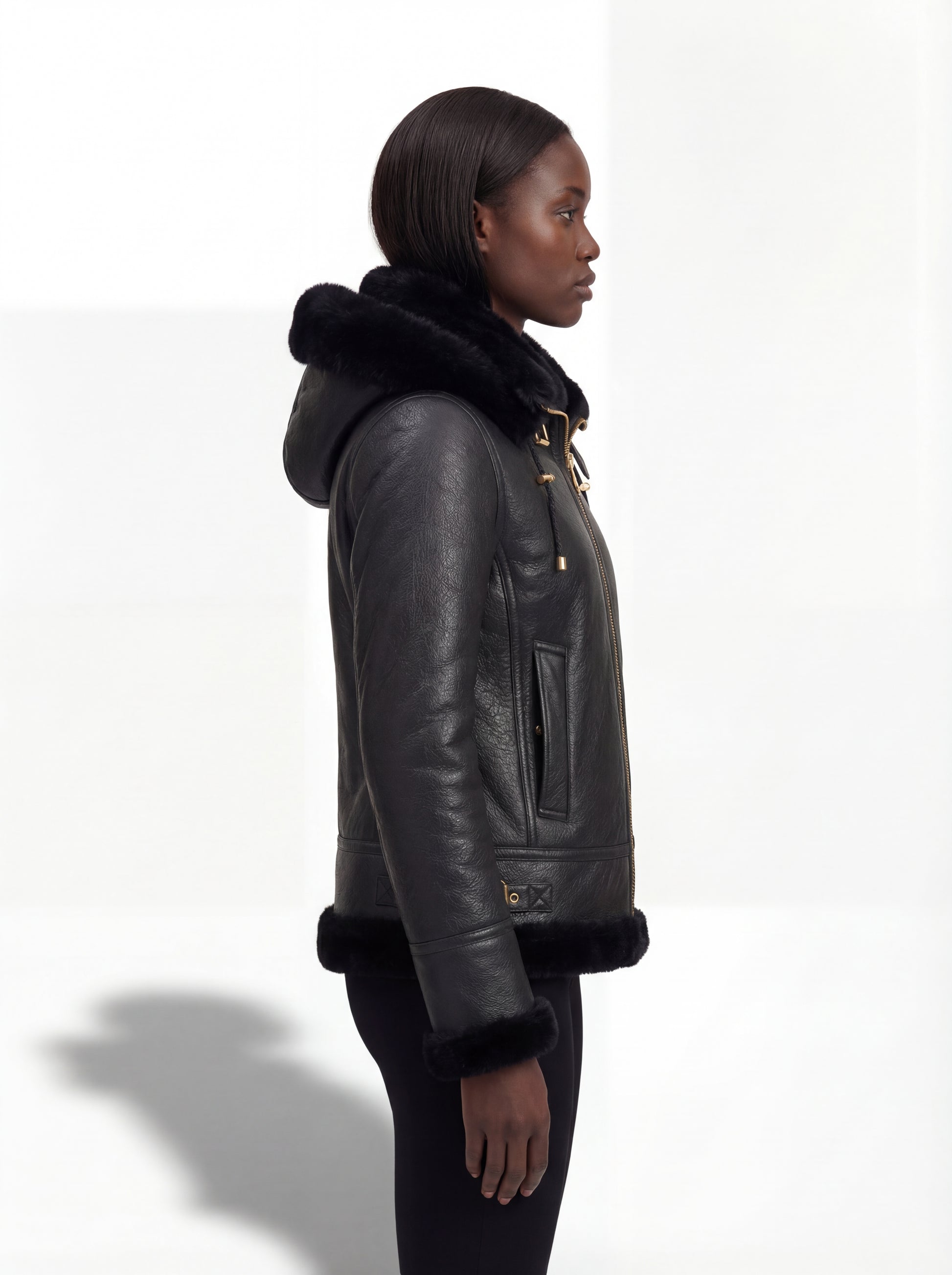 Side profile of Maverick Kira hooded shearling jacket showing leather sleeve cuffs and fitted silhouette. Maverick Jacket.