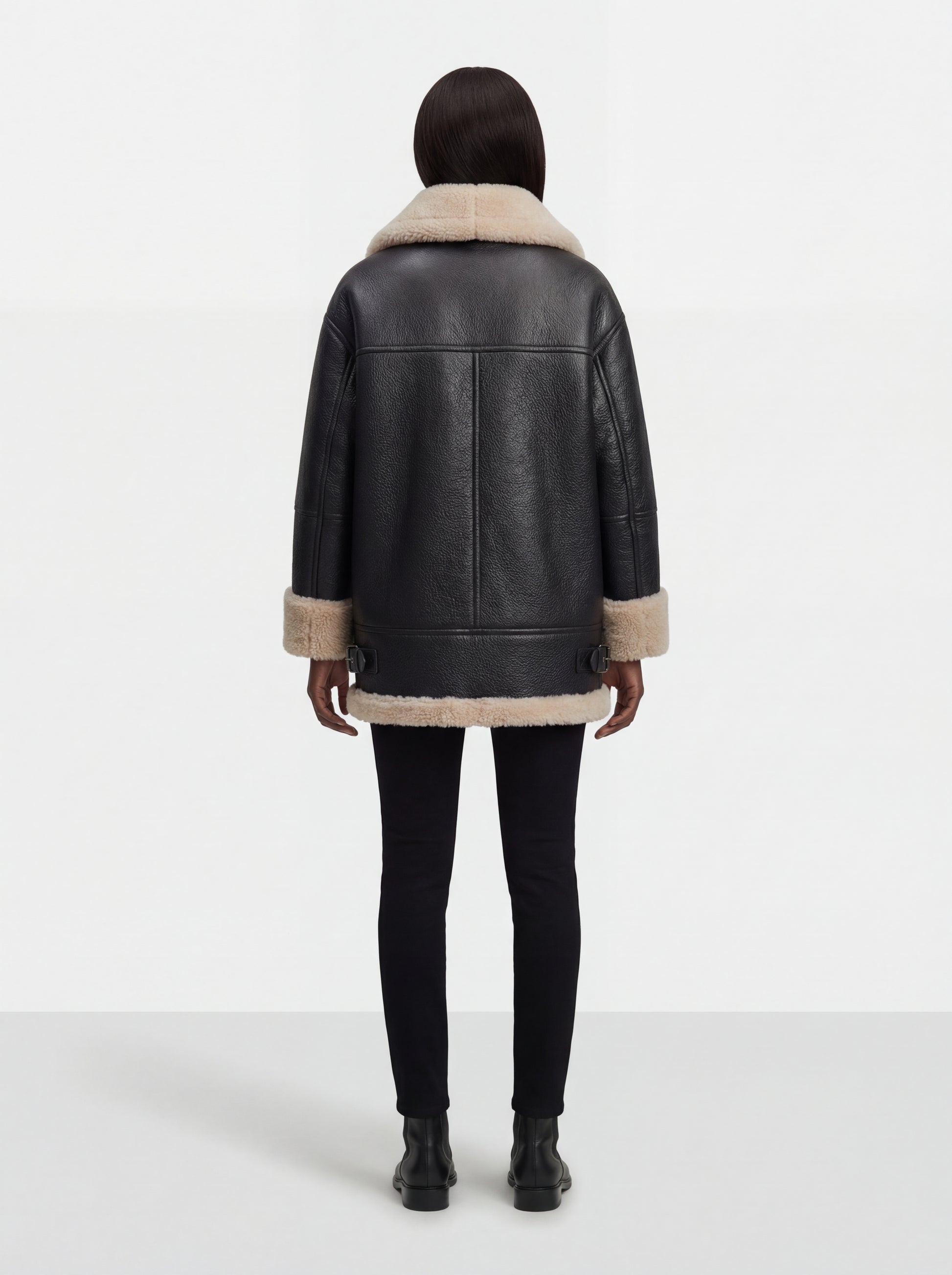 Rear view of female model wearing Maverick Lyra aviator jacket showing structured shoulder fit and shearling hem detail. Maverick Jacket.
