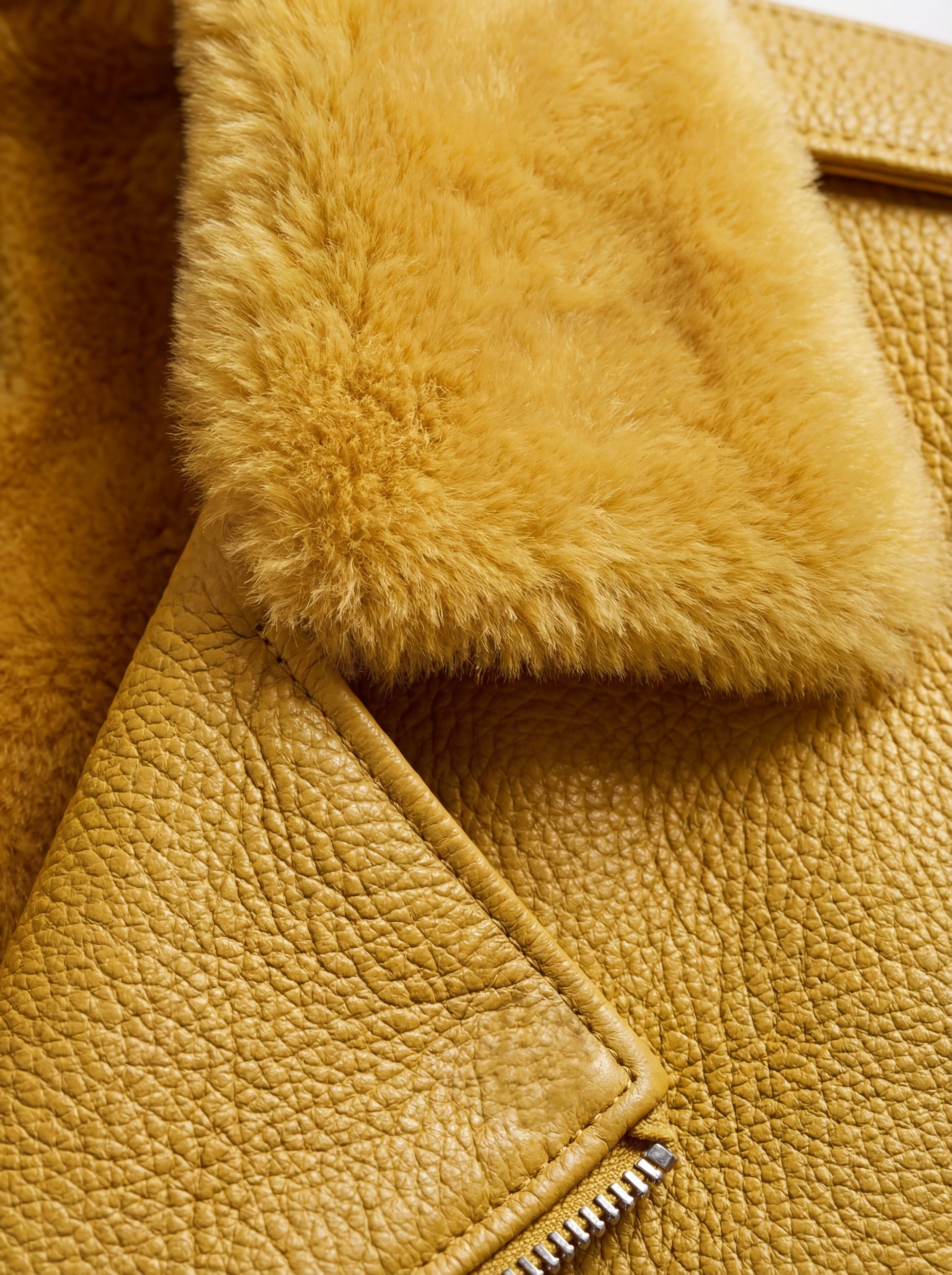Macro shot of yellow pebbled leather grain and plush shearling collar texture on biker jacket. The Solar by Maverick Jacket.