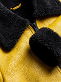 Macro shot of yellow pebbled leather grain and dense black shearling wool texture on collar. The Voltage by Maverick Jacket.