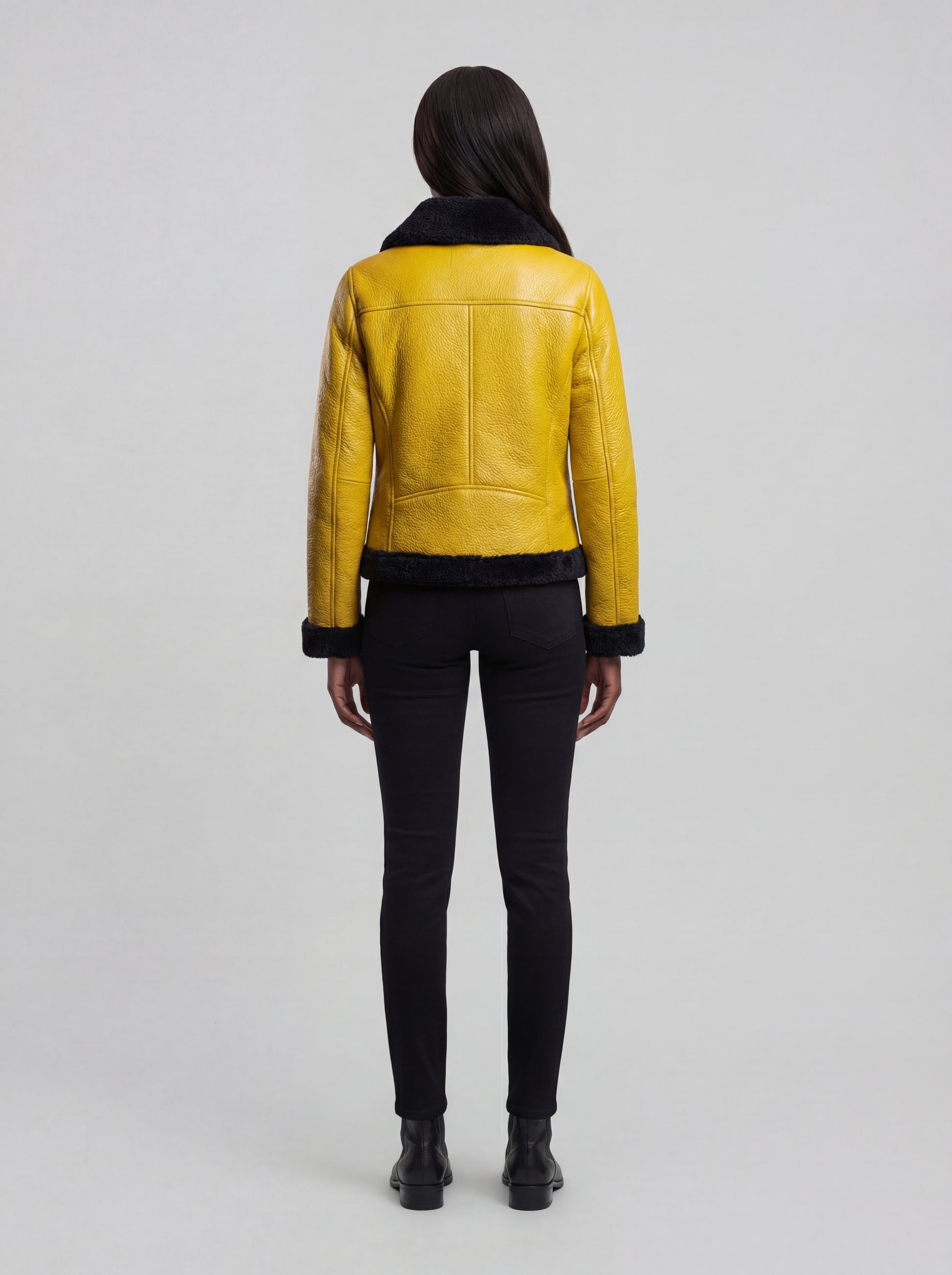 Rear view of female model wearing Maverick Voltage shearling jacket showing structured shoulder fit and clean back paneling. Maverick Jacket.
