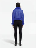 Rear view of female model wearing Maverick Cobalt shearling biker jacket showing structured shoulder fit and blue fur hemline. Maverick Jacket.